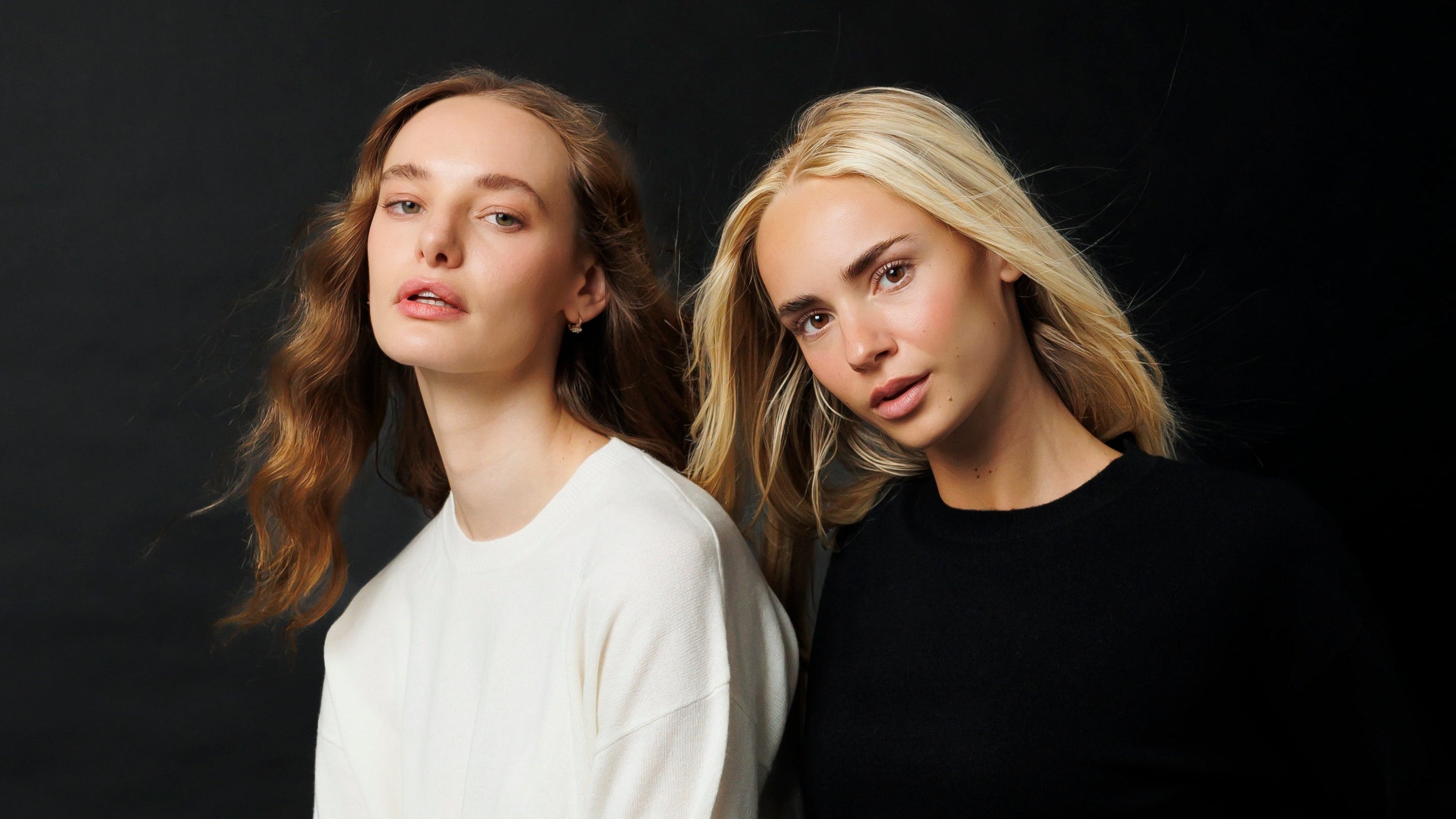 Two people sitting close together against a black background